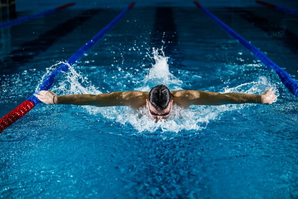 Hombre nadando estilo mariposa en piscina para quemar calorias y adelgazar